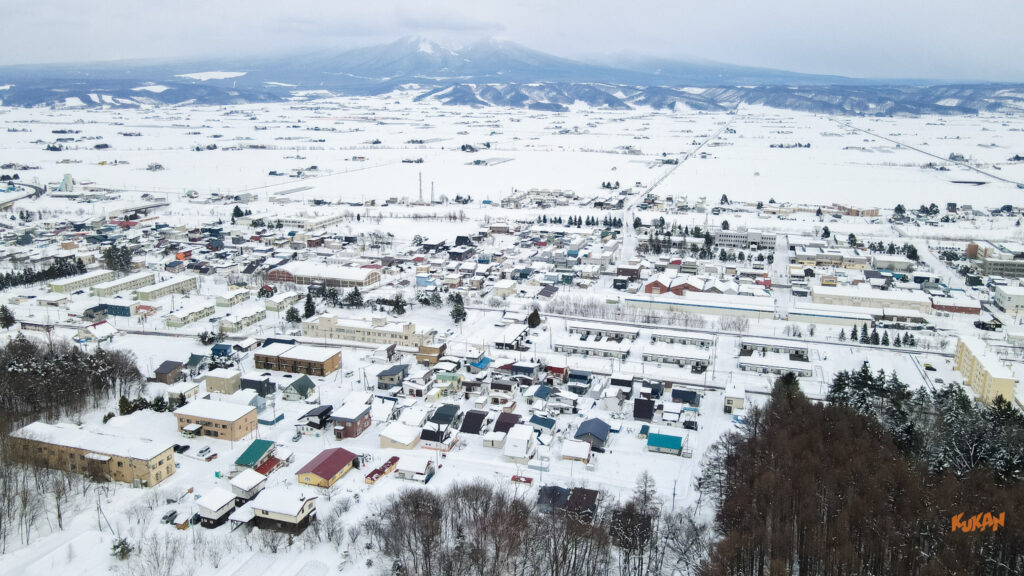 Aerial view of Nakafurano Okamachi. Snow-covered cityscape with the Tokachi Mountain Range.