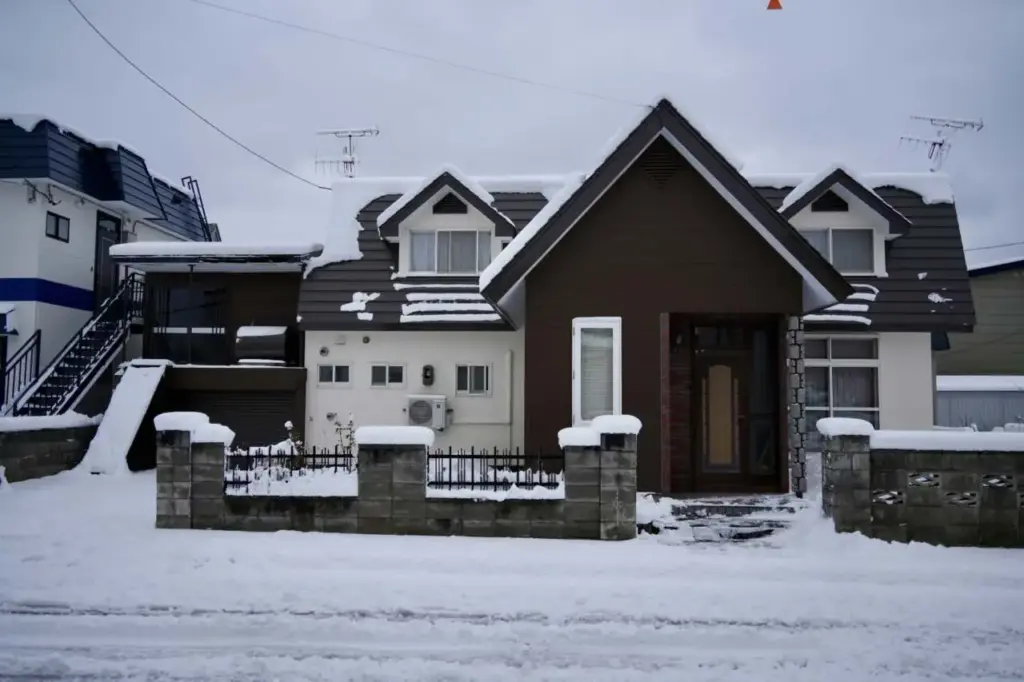 雪景下的獨棟住宅外觀與石砌圍牆