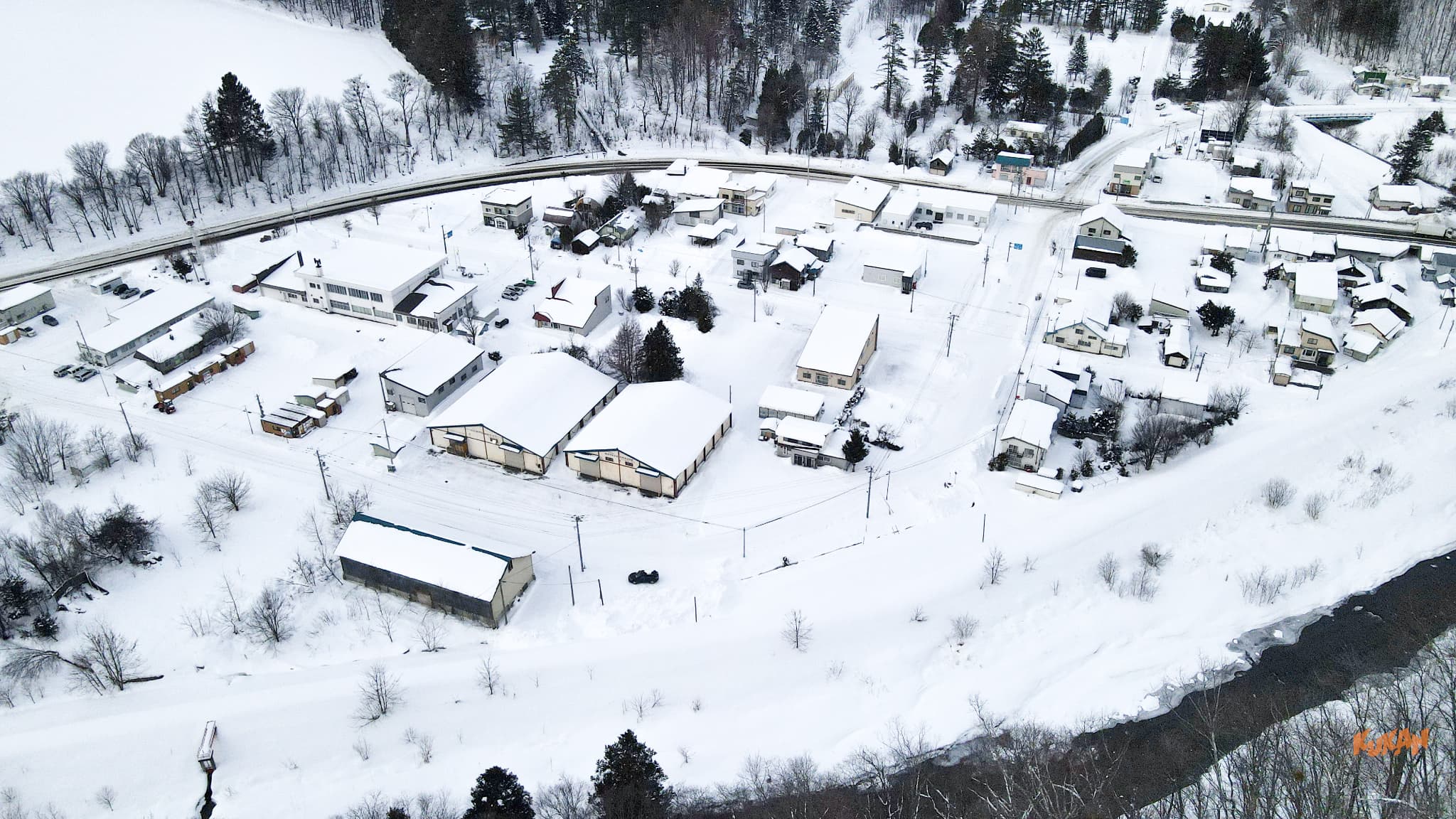 High-angle aerial drone shot of the snowy Furano Higashiyama neighborhood.